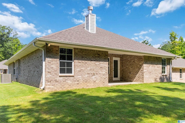 rear view of house featuring central AC and a lawn