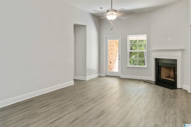 unfurnished living room with a towering ceiling, hardwood / wood-style flooring, and ceiling fan