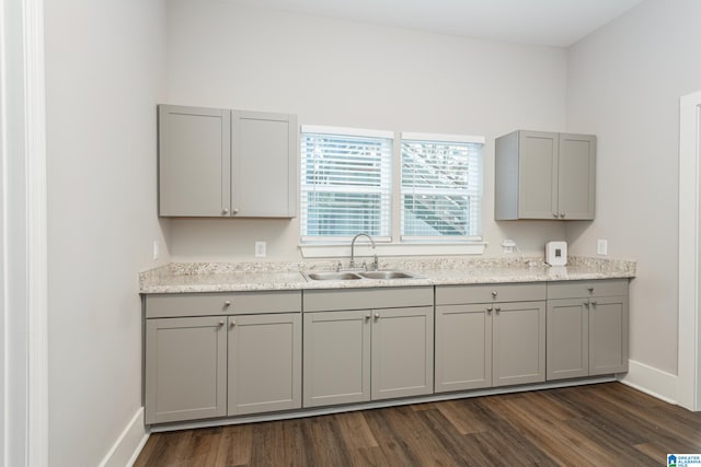 kitchen with gray cabinets, sink, light stone countertops, and dark hardwood / wood-style flooring