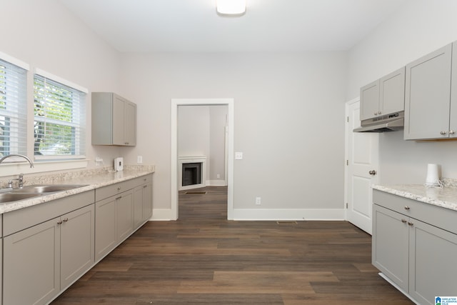 kitchen featuring dark wood-type flooring, light stone counters, sink, and gray cabinetry