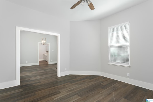 spare room with dark wood-type flooring and ceiling fan with notable chandelier