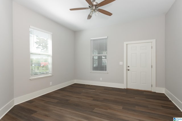 empty room with dark wood-type flooring, ceiling fan, and a healthy amount of sunlight