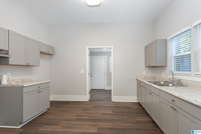 kitchen with dark hardwood / wood-style floors, light stone countertops, sink, and gray cabinetry