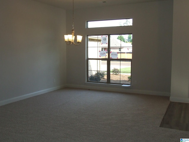 spare room with a notable chandelier and carpet flooring