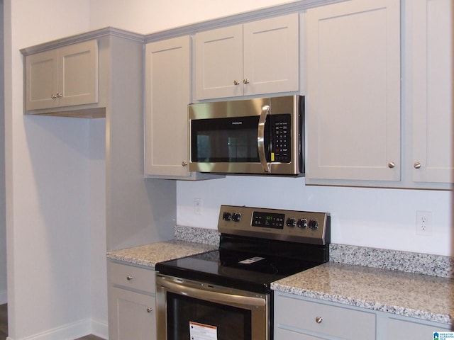 kitchen featuring light stone countertops, appliances with stainless steel finishes, and gray cabinets