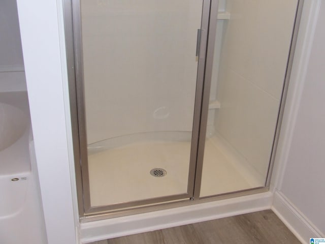 bathroom featuring wood-type flooring and an enclosed shower