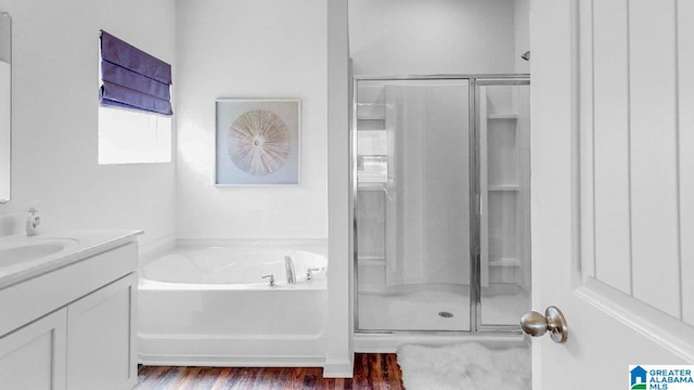 full bath featuring a bath, wood finished floors, a shower stall, and vanity