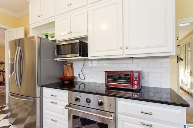 kitchen with ornamental molding, dark countertops, white cabinetry, and stainless steel appliances