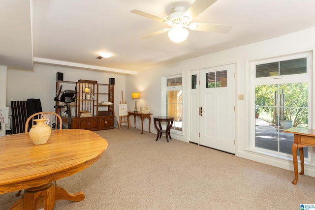 dining space featuring light colored carpet and ceiling fan