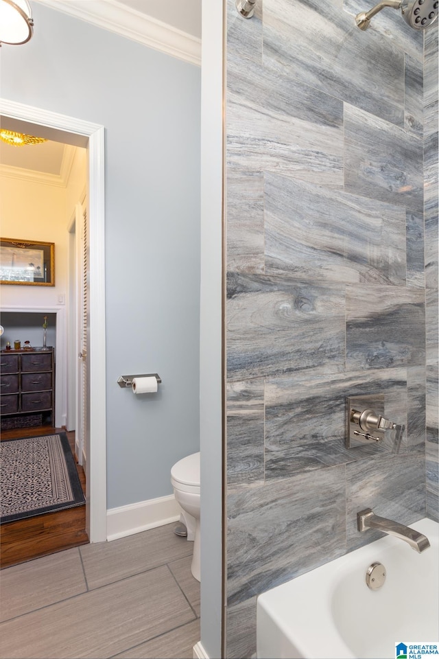 bathroom featuring toilet, crown molding, tiled shower / bath combo, and tile patterned flooring