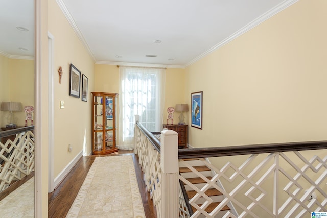 corridor with baseboards, wood finished floors, an upstairs landing, and ornamental molding