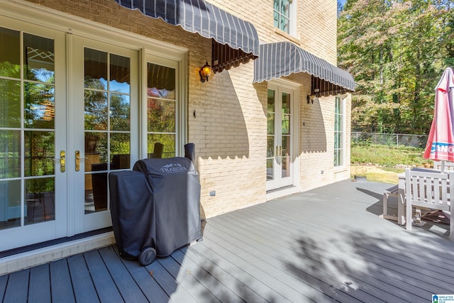 wooden deck featuring grilling area, french doors, and fence