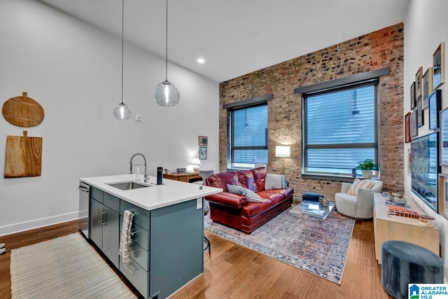 living room featuring a towering ceiling, brick wall, wood-type flooring, and sink