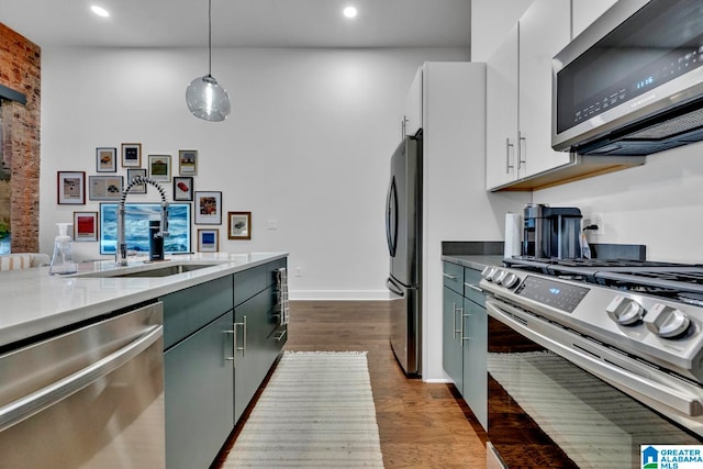 kitchen featuring sink, white cabinetry, stainless steel appliances, pendant lighting, and hardwood / wood-style flooring