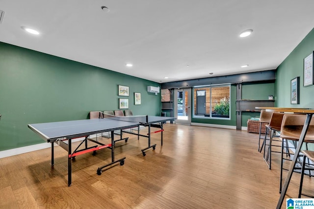 playroom with a wall mounted air conditioner and light wood-type flooring