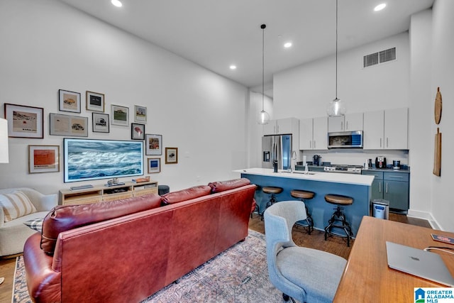 living room featuring sink, a high ceiling, and light wood-type flooring