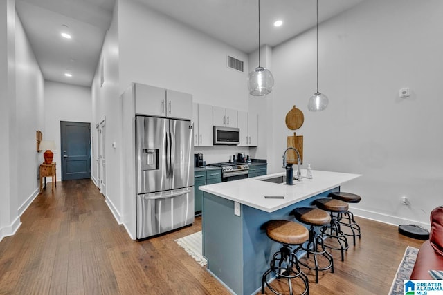 kitchen with a high ceiling, a breakfast bar area, hanging light fixtures, sink, and appliances with stainless steel finishes