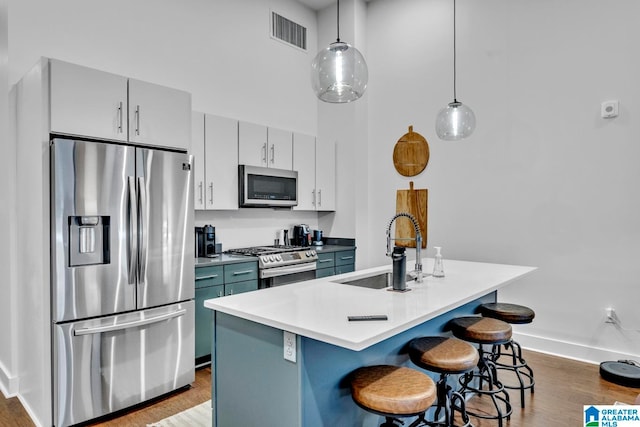 kitchen featuring stainless steel appliances, sink, a breakfast bar, pendant lighting, and dark hardwood / wood-style flooring