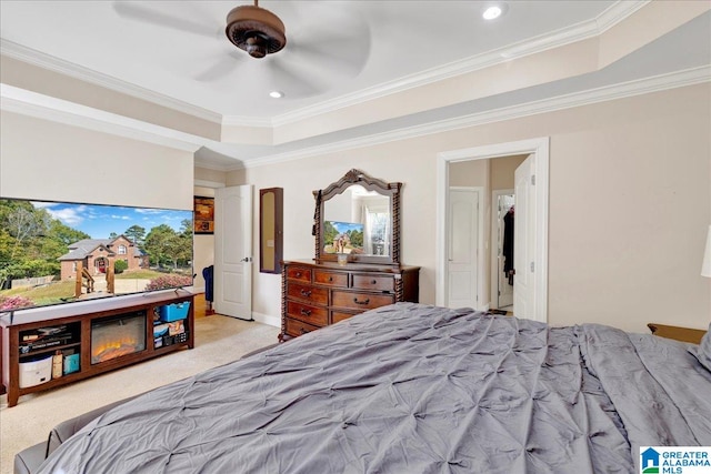 carpeted bedroom featuring ceiling fan, crown molding, and a raised ceiling