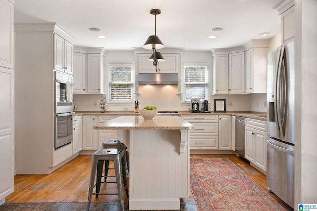 kitchen with light hardwood / wood-style floors, appliances with stainless steel finishes, pendant lighting, and white cabinets