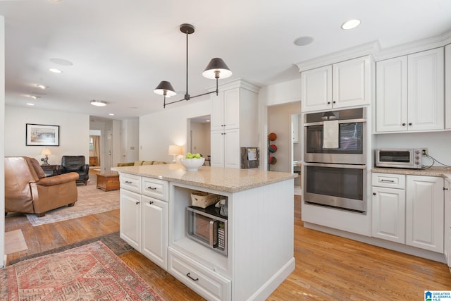 kitchen featuring light hardwood / wood-style floors, white cabinets, stainless steel appliances, and hanging light fixtures