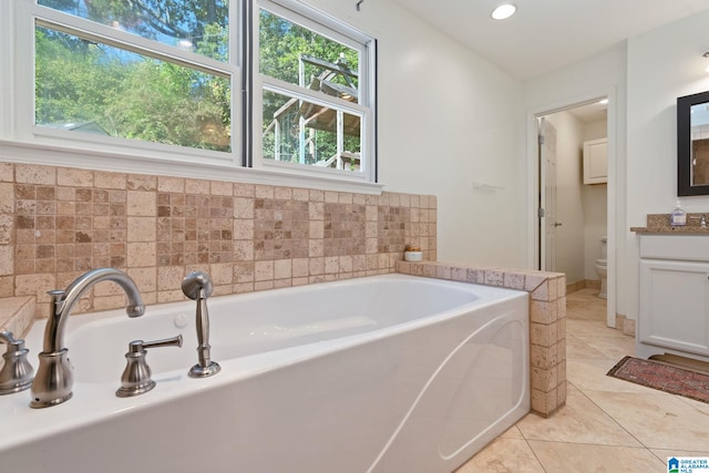 bathroom featuring a healthy amount of sunlight, vanity, toilet, and a bathing tub