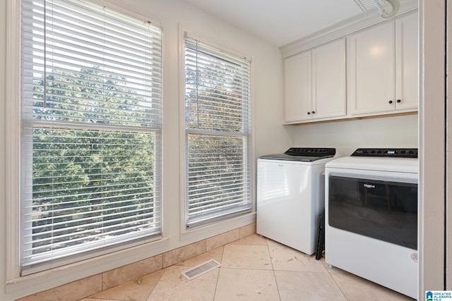 clothes washing area with independent washer and dryer, light tile patterned floors, and cabinets