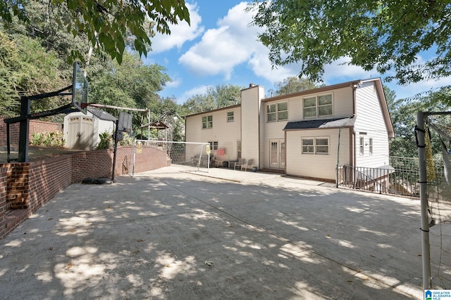 rear view of property with a storage unit and a patio area