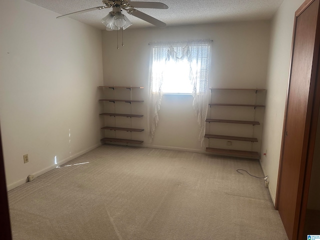 empty room with ceiling fan, light carpet, and a textured ceiling