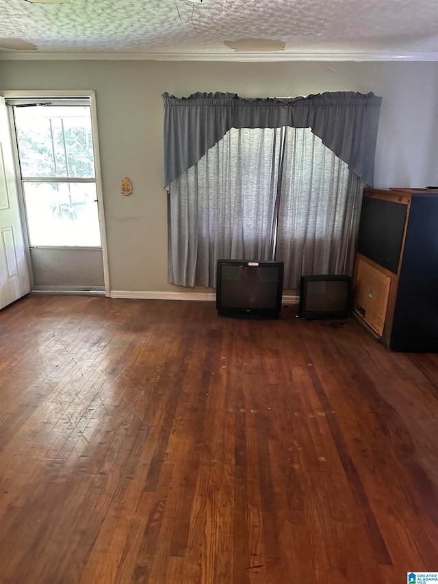 empty room featuring crown molding, a textured ceiling, and dark hardwood / wood-style flooring