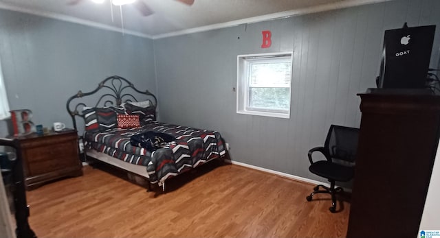 bedroom with ceiling fan, wood walls, ornamental molding, and hardwood / wood-style floors