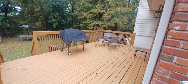 wooden deck with a trampoline and a grill