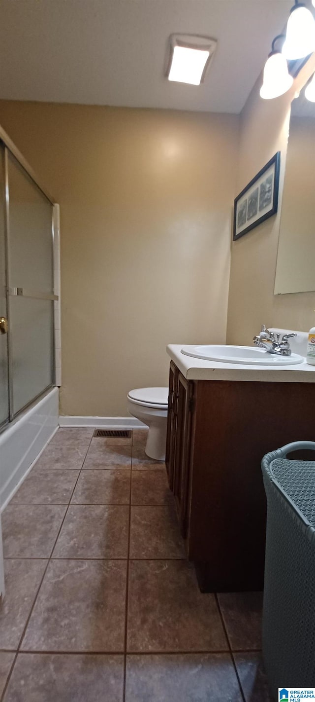 full bathroom featuring vanity, combined bath / shower with glass door, toilet, and tile patterned flooring