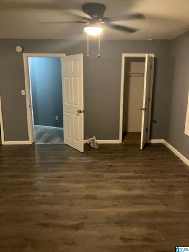 unfurnished bedroom featuring dark wood-style floors, a closet, ceiling fan, and baseboards