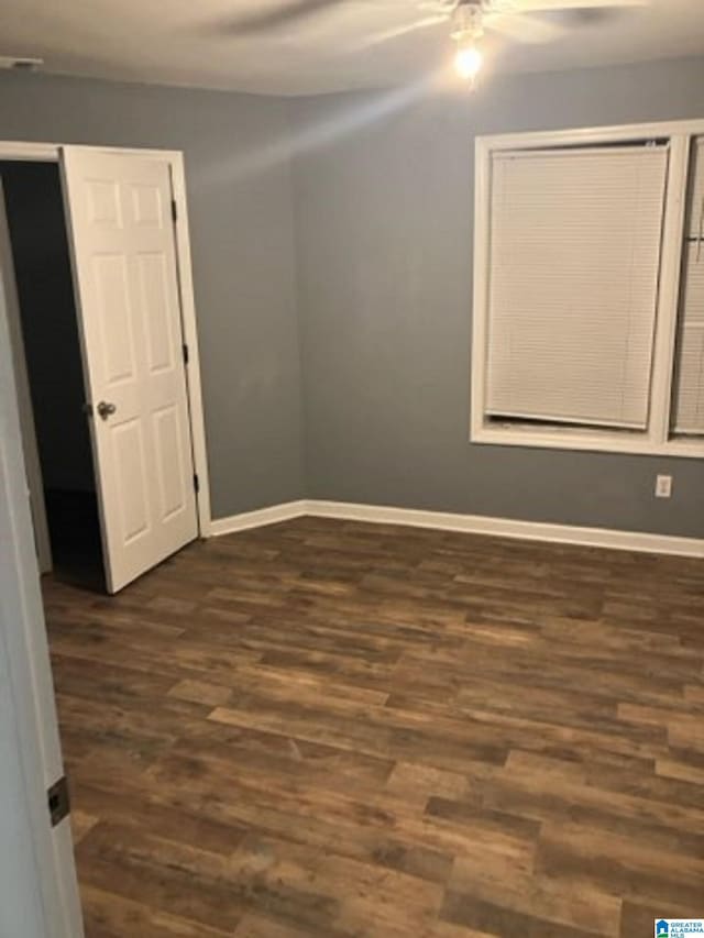 spare room featuring a ceiling fan, baseboards, and dark wood finished floors