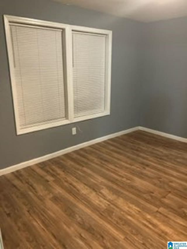spare room featuring wood finished floors and baseboards