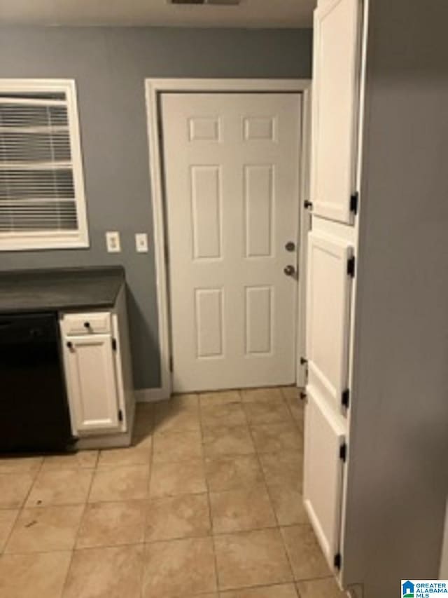 doorway featuring light tile patterned floors and baseboards