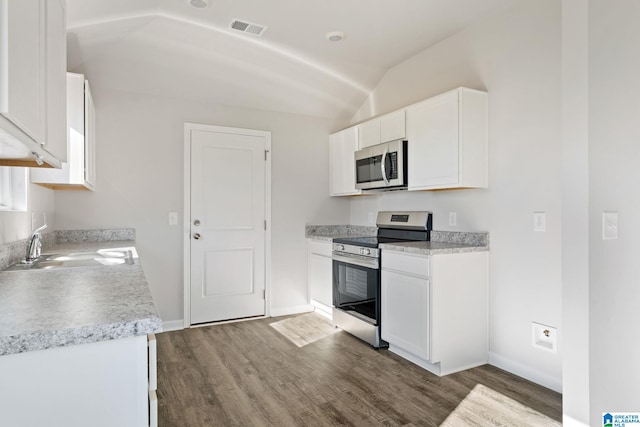 kitchen with lofted ceiling, sink, dark hardwood / wood-style floors, stainless steel appliances, and white cabinets