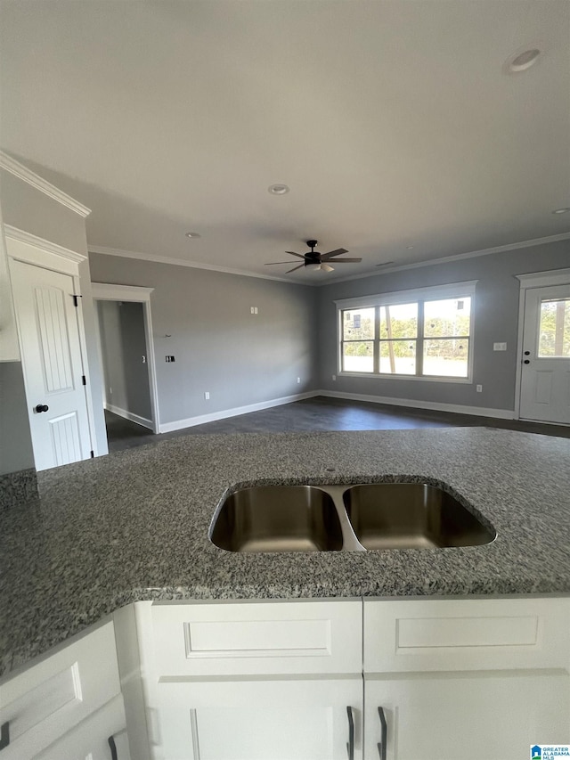 kitchen with ceiling fan, white cabinets, dark stone counters, and crown molding