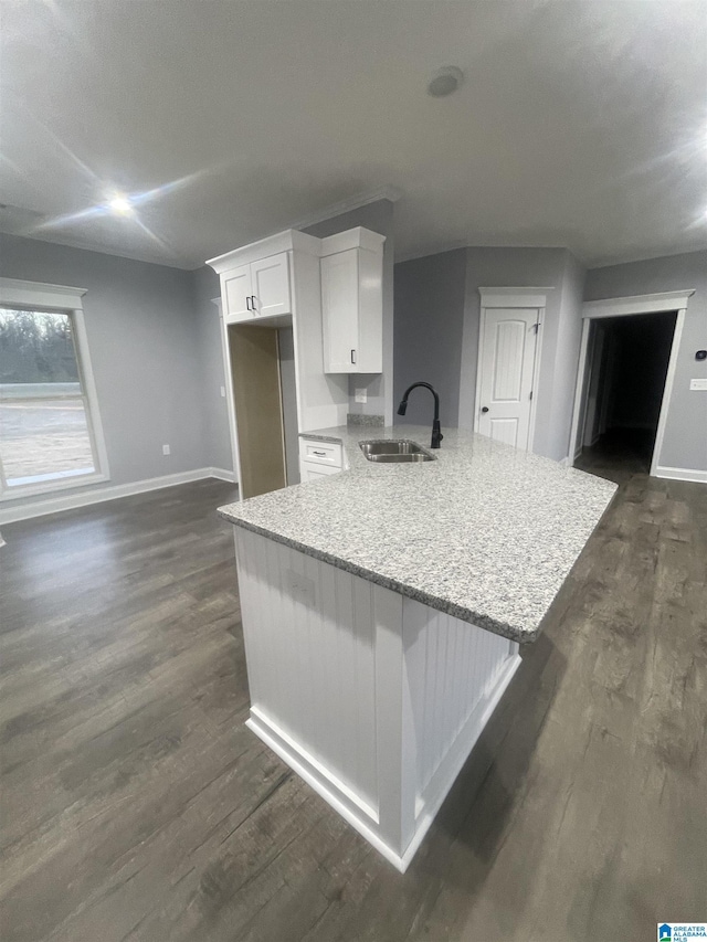 kitchen with dark hardwood / wood-style floors, kitchen peninsula, sink, white cabinetry, and light stone counters