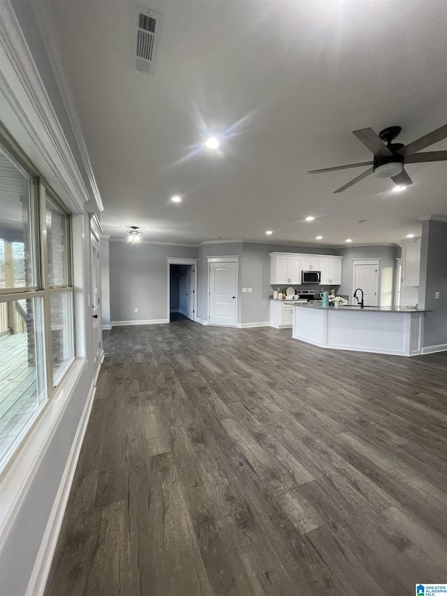 unfurnished living room with ceiling fan, dark hardwood / wood-style floors, and crown molding