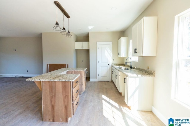 kitchen featuring light wood finished floors, a center island, a wealth of natural light, and a sink