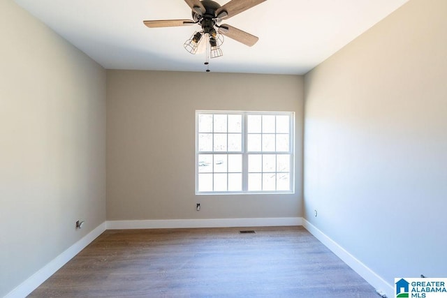 empty room with visible vents, wood finished floors, baseboards, and ceiling fan