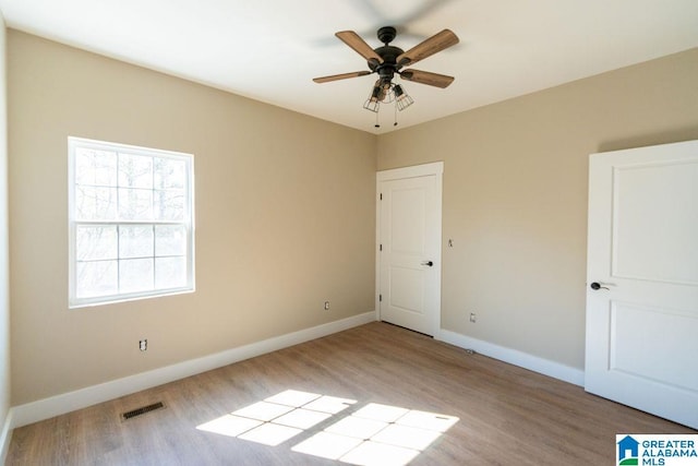 unfurnished bedroom with ceiling fan, visible vents, baseboards, and wood finished floors