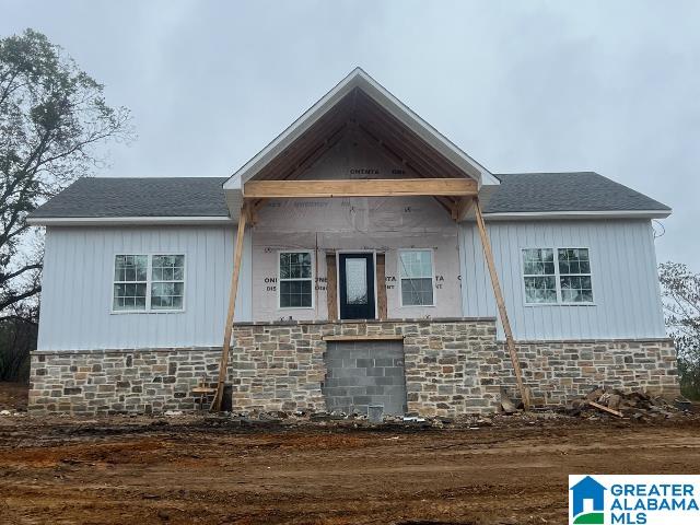 view of front of home featuring stone siding and a shingled roof