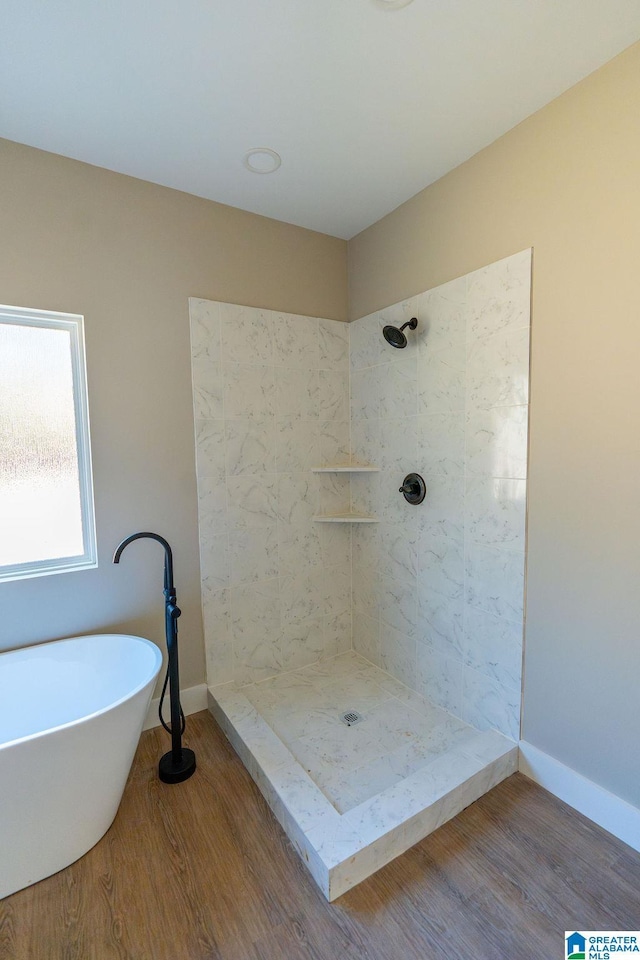 full bathroom featuring wood finished floors, baseboards, a tile shower, and a freestanding bath