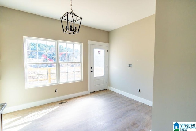 interior space featuring wood finished floors, baseboards, visible vents, and a chandelier