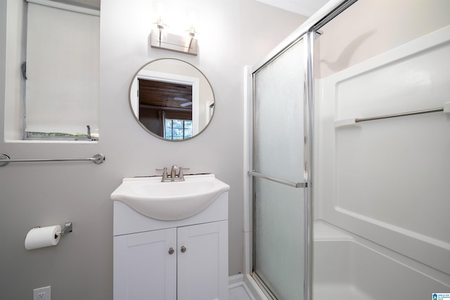 bathroom with vanity, a shower with shower door, and a healthy amount of sunlight