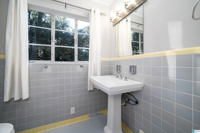 bathroom featuring toilet and tile walls