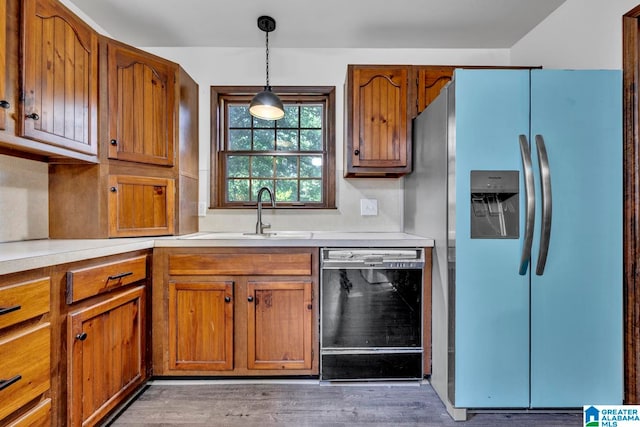 kitchen featuring decorative light fixtures, dishwasher, light hardwood / wood-style floors, stainless steel refrigerator with ice dispenser, and sink